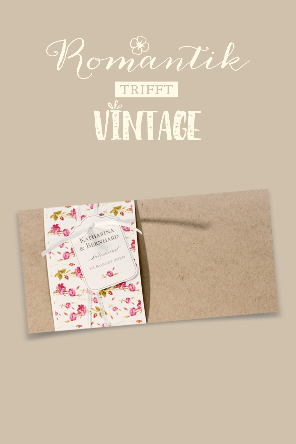 Hochzeitseinladung aus braunem Kraftkarton, links umfasst von einer weißen, mit rosa Blümchen bedruckten Banderole, sowie einem weißen Bändchen an welches ein kleines Kärtchen geknüpft ist.
