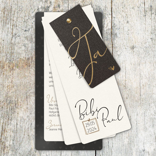 Vergrößerte Abbildung der Karte Hochzeitseinladungen als Fächer. Edle Materialien, wie perlmuttartig schillernder cremefarbener Karton oder schwarzer, golden schillernder Metallic-Karton. Zusammengefasst werden vier Blätter durch eine Messing-Niete.