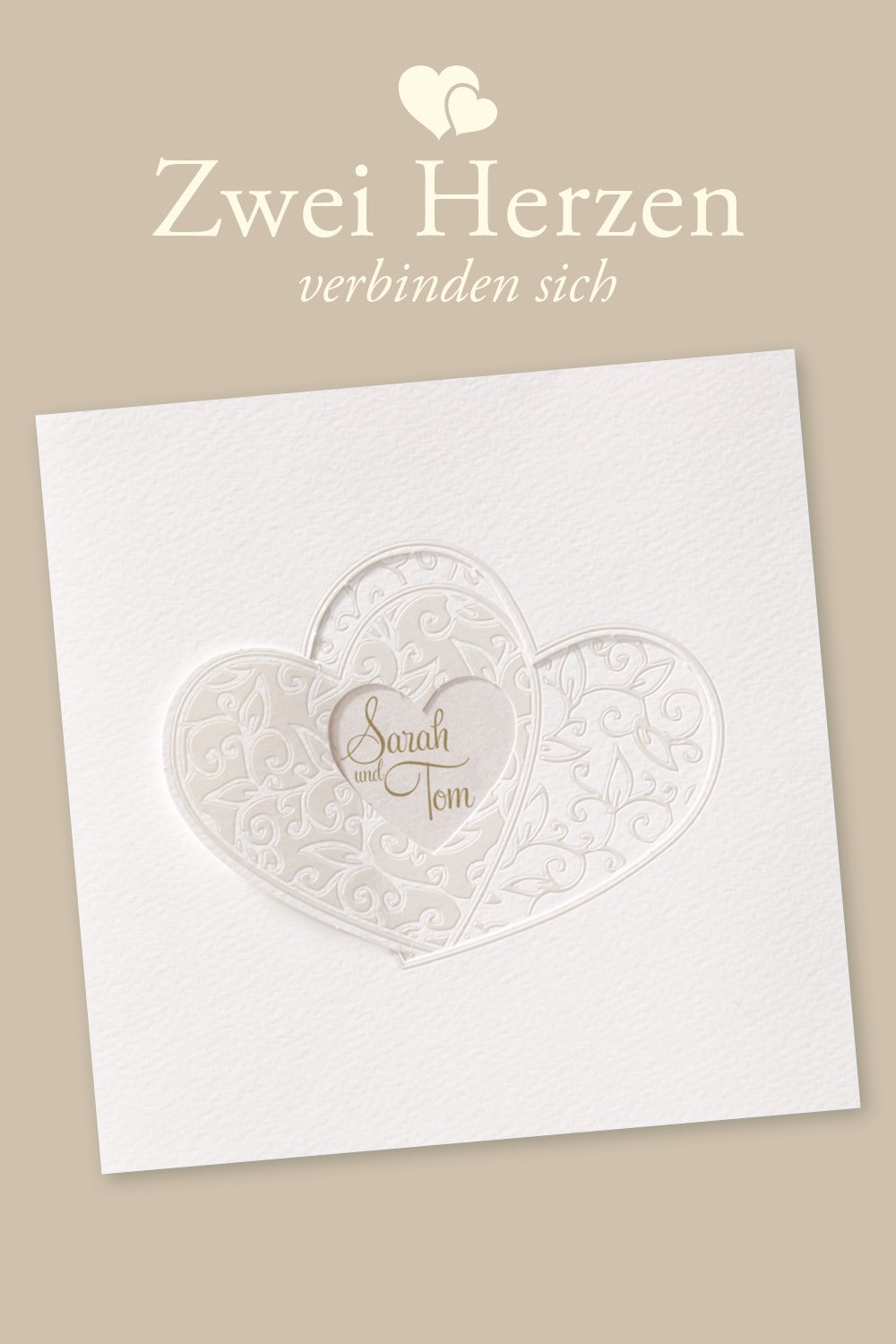 Weiße Hochzeitseinladungen mit zwei verschlungenen Herzen, die auch als Verschluss für die Karte dienen. Verziert mit stilisierten Blumenranken.