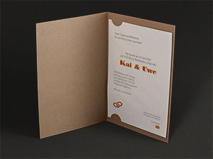 Vergrößerte Abbildung Stehende, aufgeklappte Einladungskarte mit eingestecktem, bedruckten Texteinleger.